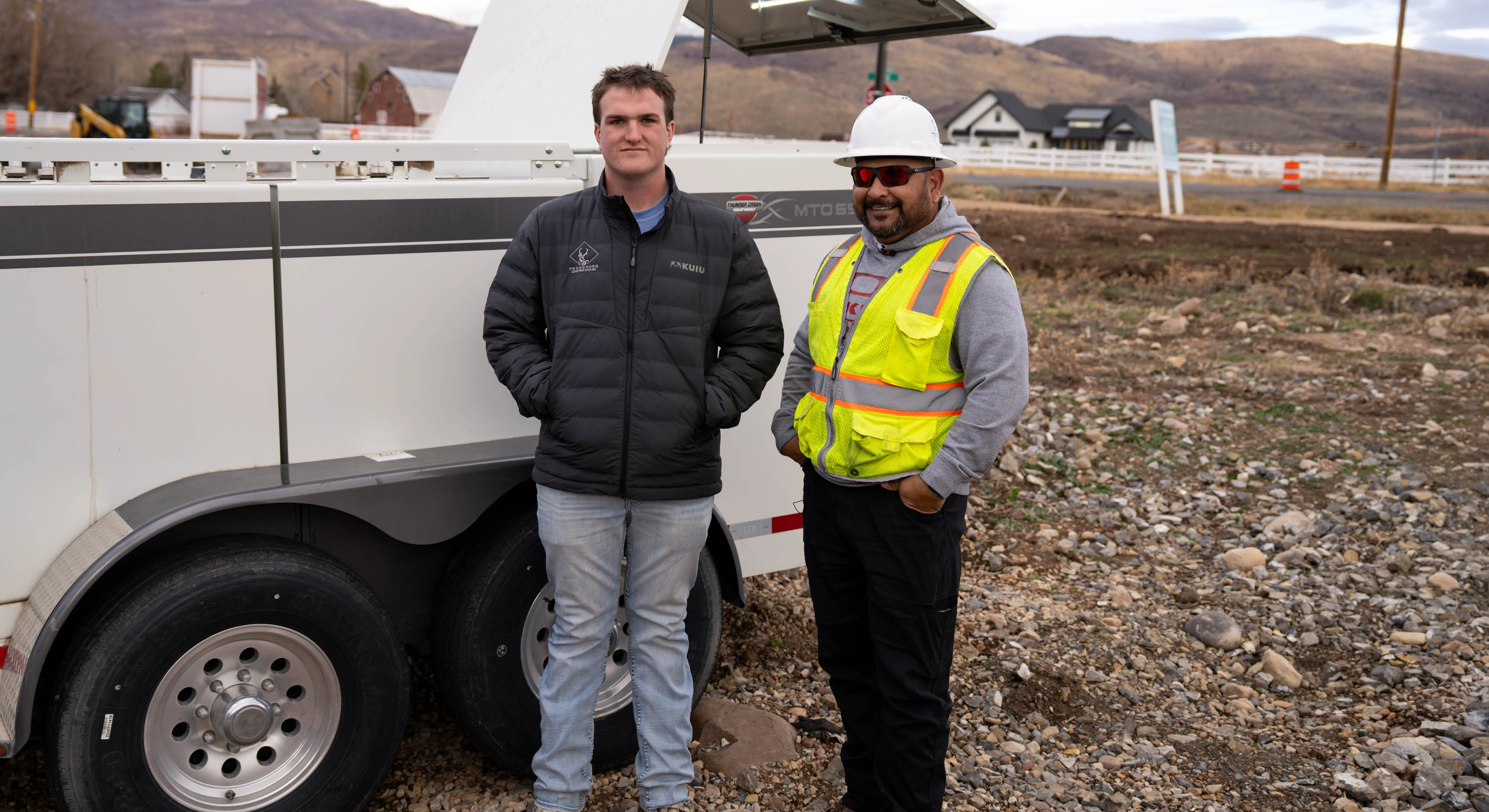 Two men standing next to a Thunder Creek Fuel and Oil Trailer on a construction jobsite